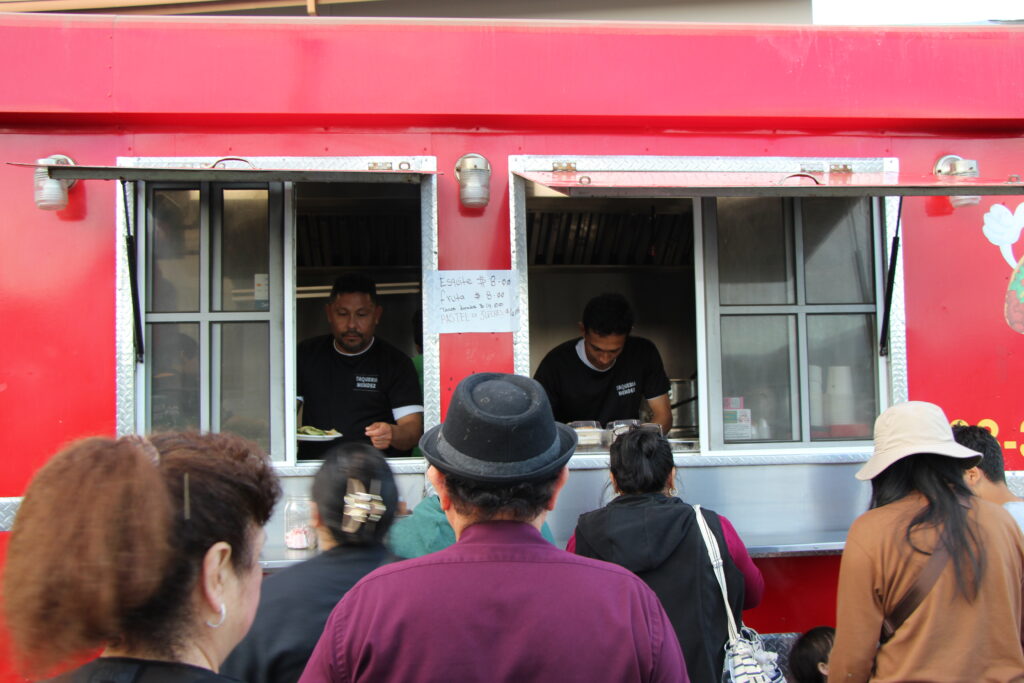 A group standing in line waiting for tacos from a foodtruck