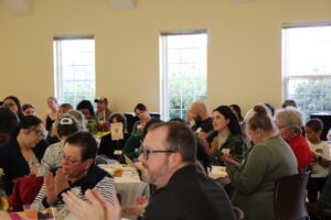 Guests at the Mildred Davy event seated, clapping for a speaker.
